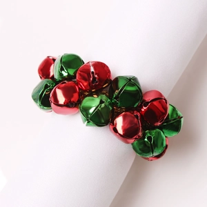Détail d'un rond de serviette avec cloches rouges et vertes sur serviette blanche