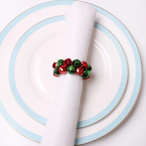 Détail d'un rond de serviette festif en clochettes rouges et vertes sur assiette blanche