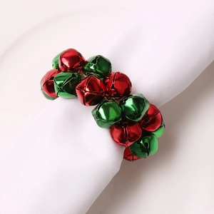 Détail d'un rond de serviette avec cloches en métal rouge et vert sur serviette blanche