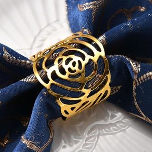 Elegant gold hollow rose flower metal napkin ring on navy blue napkin with dinner plate