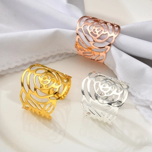 Detailed view of hollow metal rose napkin rings in gold, silver, and rose gold on white plates