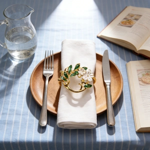 Gardenia flower napkin ring with gold band and green leaves on elegant table setting