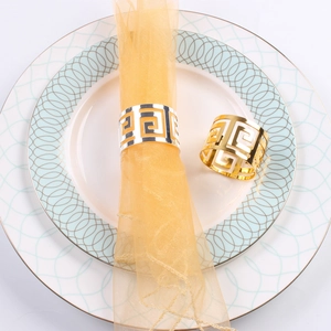 Detail of gold and silver hollow napkin rings with raindrops pattern on white plates