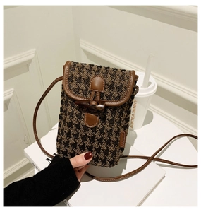Detail of checkered tweed mini bag featuring a wooden horn toggle and brown leather strap