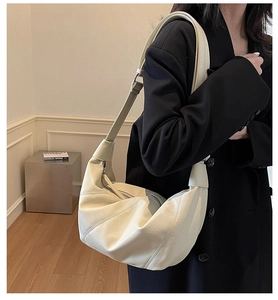 Close-up of cream soft leather hobo bag featuring elegant pleats and adjustable strap
