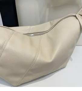 Detail of creamy beige half-moon bag showing premium lychee texture and silver zipper