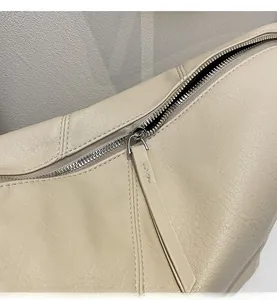 Close-up of cream leather shoulder bag with lychee texture and smooth silver zipper