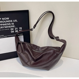 Detail of dark brown leather crescent bag with silver zipper and adjustable strap