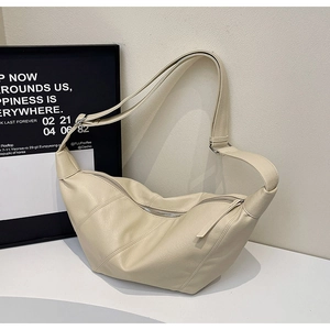 Detail of cream crescent crossbody bag with diagonal stitching and adjustable strap