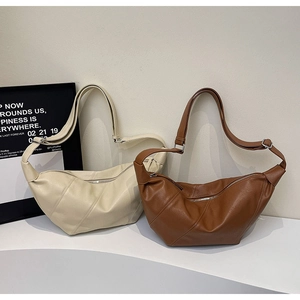 Detail view of cream and dark brown crescent dumpling bags with pleated faux leather finish