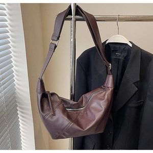 Detailed close-up of dark red leather hobo bag hanging on a metal hanger with a black suit