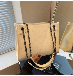 Mirror view showing V-quilted texture and metal chain strap of this cream tote bag