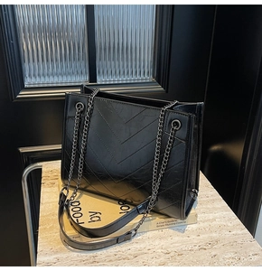 Detail of black leather tote bag featuring classic chevron stitching and chain strap
