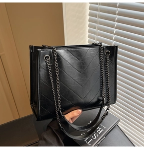 Detailed macro view of black quilted tote bag with distressed leather and chain strap