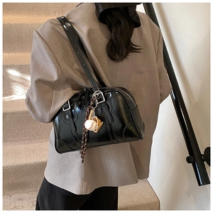Detail of glossy black patent leather bowling bag with a decorative baseball pendant