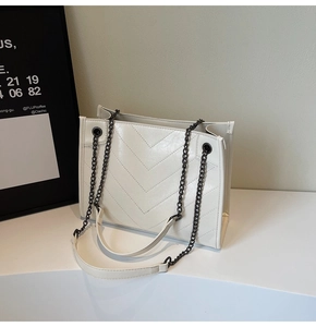 Detailed close-up of cream PU leather tote with V-shaped quilting and metal chain strap