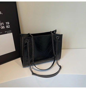 Detail of the high-quality black V-quilted faux leather tote bag with metal chain strap