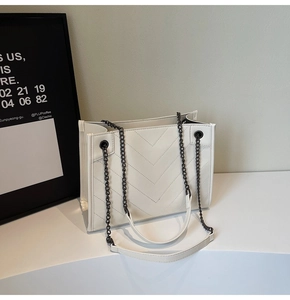 Close-up of white tote bag with V-shaped quilting and metal chain shoulder strap