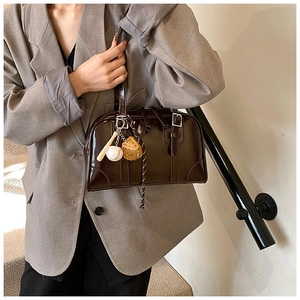 Macro view of dark brown patent leather bowling bag with vintage baseball charms