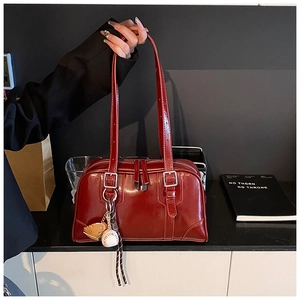 Detail of burgundy patent leather bag with baseball glove pendant and silver hardware