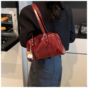 Detail of burgundy glossy leather shoulder bag with vintage buckles and baseball charm