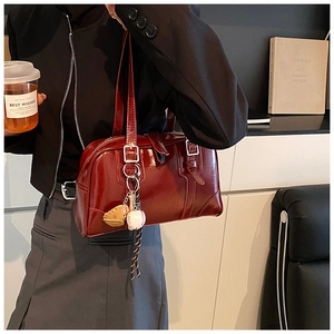 Detail of dark red patent leather Boston bag with a unique baseball theme pendant charm