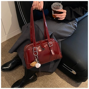 Detail of vintage dark red patent leather bowling bag with silver buckle and bag charm