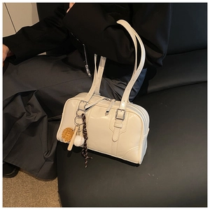 Detail of cream white faux leather tote with metal buckles and a cute baseball charm