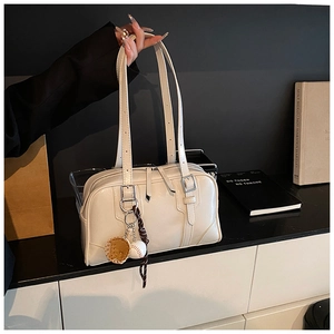 Close-up of retro cream tote bag featuring adjustable straps and baseball glove charm