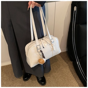 Close-up of white lychee texture boston bag with dual straps and cute bear charm