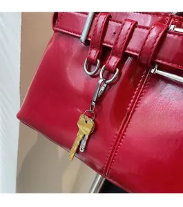 Detail of red glossy leather handbag with metallic hardware and key charms