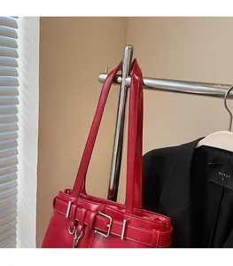 Close-up of glossy red leather shoulder bag with metallic buckle and belt detail