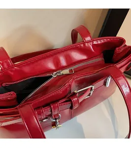 Detail view of smooth silver metal zipper and glossy red patent leather motorcycle bag