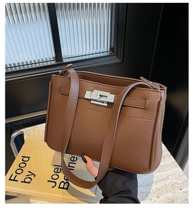 Detailed macro view of the brown lychee grain leather texture and silver twist lock on bag