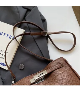 Detailed close-up of brown lychee leather shoulder bag with silver twist-lock fastener