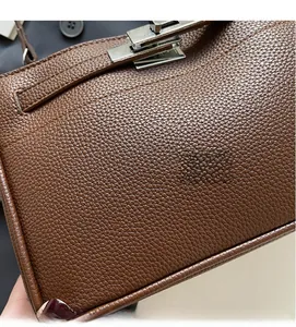 Close-up of brown grain leather texture and silver twist lock on a retro handbag