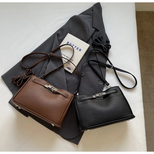Close-up of litchi grain leather handbags with metal turn-lock closure and bottom rivets