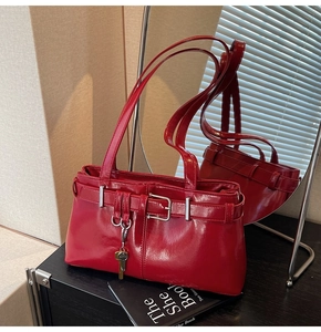 Close-up of shiny red patent leather shoulder bag with retro buckles and key pendant