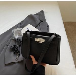 Detail of black lychee grain leather handbag with silver rotating buckle and strap