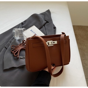 Detail of caramel pebbled leather handbag with metal turn-lock and detachable shoulder strap