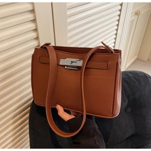 Detailed close-up of brown lychee grain leather handbag with silver metallic twist-lock