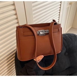 Close-up of brown litchi pattern leather bag with silver metal twist lock and strap