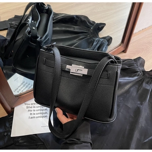 Detailed view of black litchi pattern leather Kelly bag with silver metal twist lock