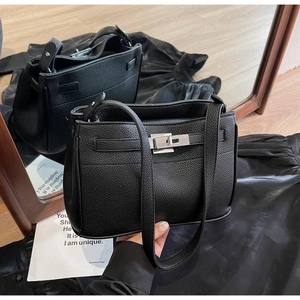 Detail of black litchi grain leather texture and silver metal twist lock on the handbag