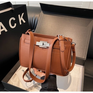 Close-up of brown litchi grain leather bag with silver twist lock in a gift box