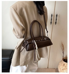 Detail of dark brown vintage bucket bag with silver buckles and woven charm