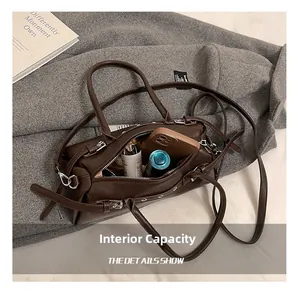 Detail view of large internal capacity showing phone and makeup inside brown boston bag