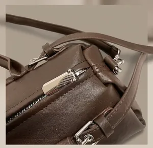 Close-up of brown leather texture with silver hardware and zipper detail on the handbag