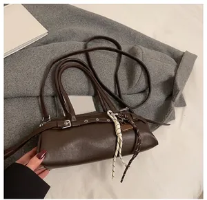 Detail view of dark brown pillow bag with silver buckle and mixed lanyards on a coat
