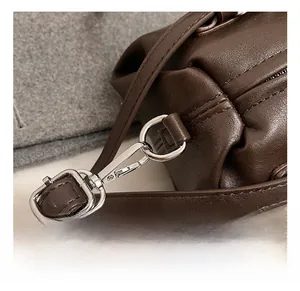 Close-up of premium silver-tone D-ring and metal hook on dark brown leather baguette bag